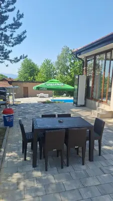 a patio with a table and chairs and a green umbrella at Vikendica El Paradiso Banjaluka in Laktaši