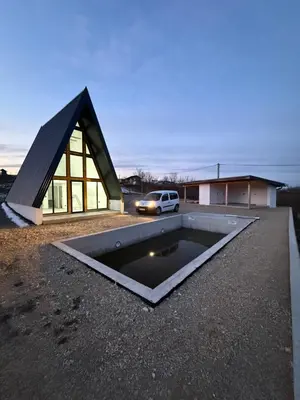 a house with a swimming pool in front of a building at Vikendica sa bazenom HUZUR in Cazin