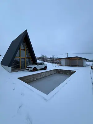 a house in the snow with a car on the roof at Vikendica sa bazenom HUZUR in Cazin