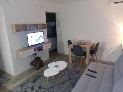 a living room with a table and a television on a wall at Apartman Ivana in Banja Luka