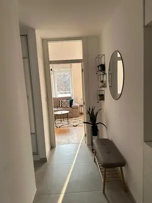 a hallway with a mirror and a chair in a room at City Apartment in Banja Luka