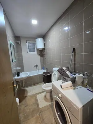a bathroom with a toilet and a sink and a washing machine at Apartman Manjić in Doboj