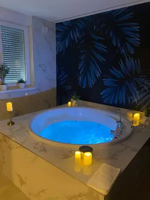 a bathroom with a large tub with candles in it at Kalipso spa apartman sa jakuzzijem in Doboj