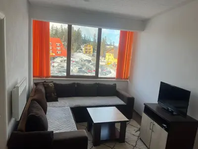 a living room with a couch and a large window at Apartman Dila in Vlasic
