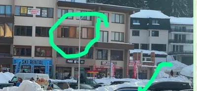 a green sign in front of a building with snow at Apartman Dila in Vlasic