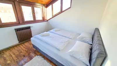 a bedroom with a bed with white sheets and pillows at Center Heritage Two-bedroom Apartment in Teslić