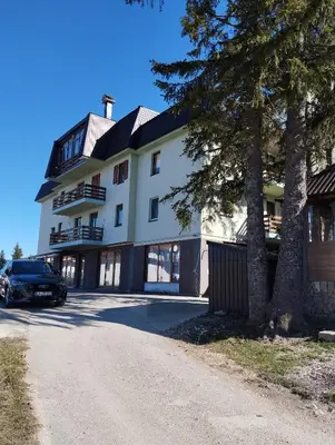 a building with a car parked in front of it at Apartman Pinja in Vlasic