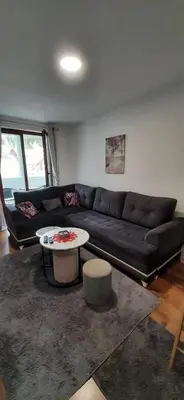 a living room with a black couch and a table at Apartman Pinja in Vlasic