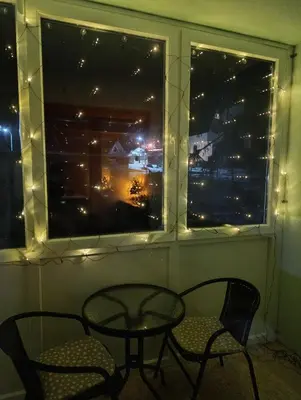 a table and chairs in front of a window with lights at Apartman Pinja in Vlasic