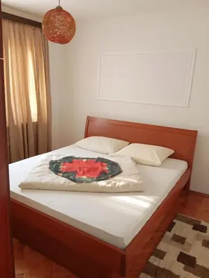a bedroom with a bed with a red flower on it at Apartman Doboj in Doboj