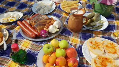 a table with plates of food on a blue checked table cloth at Apartman Iman in Kulen Vakuf