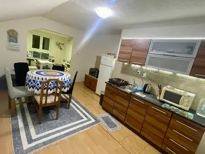a kitchen with a table and a kitchen with a microwave at Apartman Iman in Kulen Vakuf