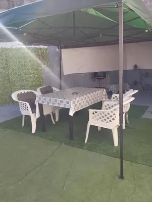 a table and chairs under a green umbrella at apartman Sara in Tuzla