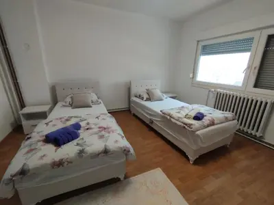 two twin beds in a room with a window at apartman Sara in Tuzla
