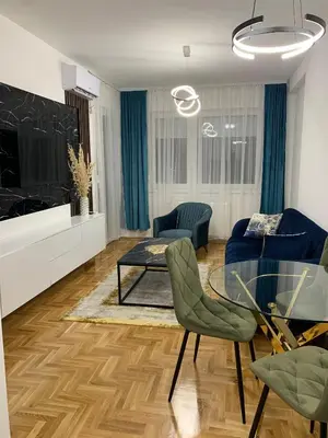 a living room with a blue couch and a glass table at Zlatni San apartman 3 in Banja Luka
