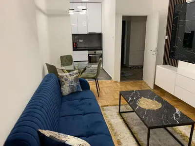 a living room with a blue couch and a table at Zlatni San apartman 3 in Banja Luka