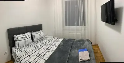 a bedroom with a black and white bed and a window at Zlatni San apartman 3 in Banja Luka