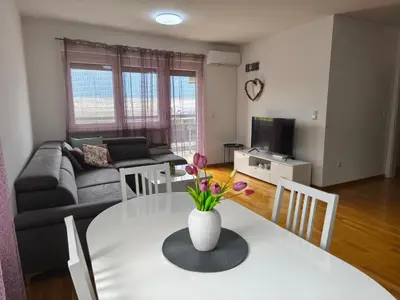 a living room with a table with a vase of flowers on it at Apartman Sedra in Bihać