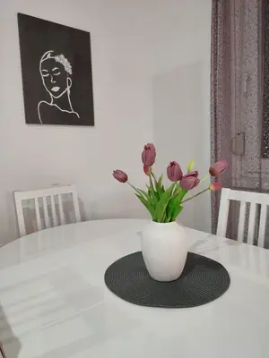 a white vase with flowers sitting on a table at Apartman Sedra in Bihać