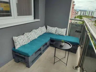 a bench on a balcony with a table and a window at Apartman Sedra in Bihać