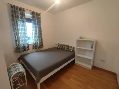 a small bedroom with a bed and a window at Apartman Sedra in Bihać