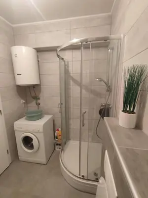 a bathroom with a shower and a washing machine at Apartman Sedra in Bihać