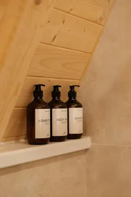 three bottles sitting on a shelf in a bathroom at Hygge house in Banja Luka
