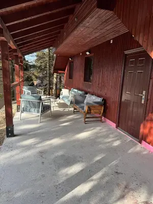 a covered porch of a red building with a wooden door at Mountain Mia in Šišava