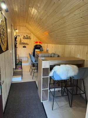 a room with a wooden ceiling and a bar with stools at Mountain Mia in Šišava