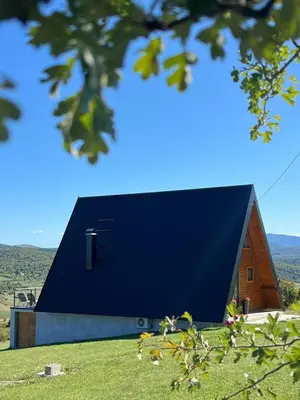a building with a black roof on top of a field at Vikendica miRAJ Manjaca in Gornje Ratkovo