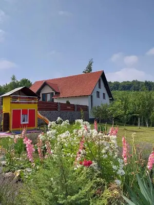 a house with a garden with flowers in front of it at Apartman HADŽILUK in Bugojno