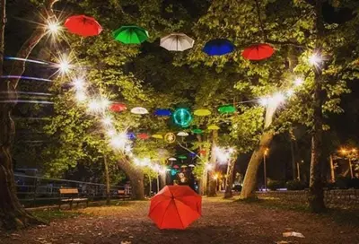 a red umbrella sitting on the ground in a park at night at Apartman Nafo in Bihać