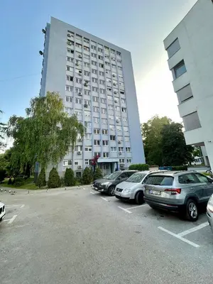 a large white building with cars parked in a parking lot at Studio Bulevar in Banja Luka