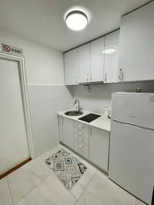 a white kitchen with a sink and a refrigerator at Studio Bulevar in Banja Luka