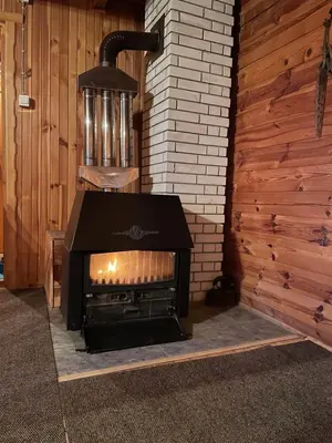 a fireplace in a room next to a wooden wall at Cozy Wooden Cottage in Banja Luka