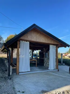 a gazebo with white curtains and a table at Cozy Wooden Cottage in Banja Luka