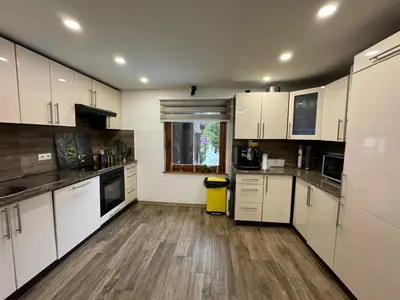 a kitchen with white cabinets and a wooden floor at Villa Gabi Vlašić in Travnik