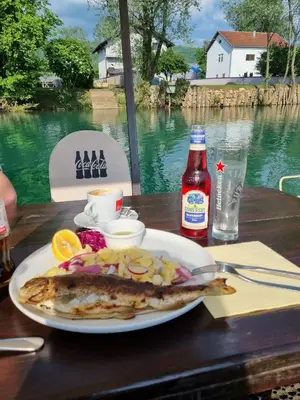 a fish on a plate on a table with a drink at Ferienwohnung Sabina in Bosanska Krupa