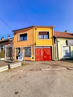 a yellow house with red doors on a street at Stan na dan Relax in Bosanska Dubica