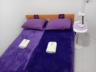 a purple bed with two white towels on it at Apartman MED in Doboj