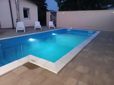 a swimming pool with two chairs and a table at Villa Aida in Bihać