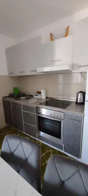a kitchen with a stove and two chairs in it at Apartman Rubin20 in Doboj