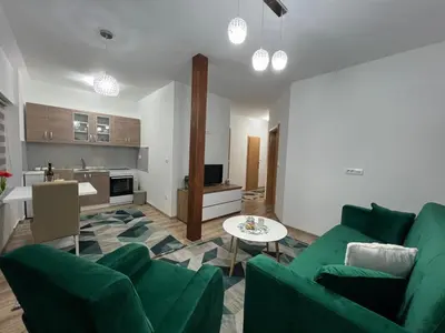 a living room with green furniture and a kitchen at Apartman Mrša in Livno