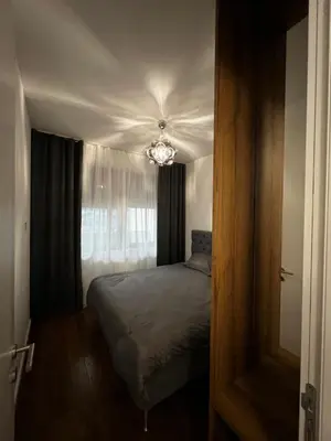 a small bedroom with a bed and a chandelier at Metropolis Apartman in Banja Luka