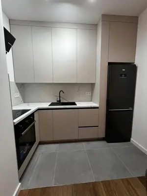 a kitchen with white cabinets and a black refrigerator at Metropolis Apartman in Banja Luka