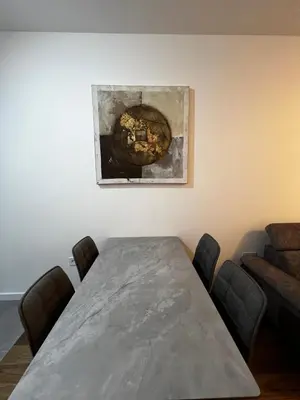 a dining room with a table and a painting on the wall at Metropolis Apartman in Banja Luka