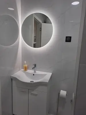 a white bathroom with a sink and a mirror at Apartman NINA in Doboj