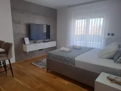 a bedroom with a large bed and a television at Apartman NINA in Doboj