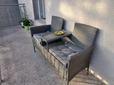 a wicker chair sitting next to a wall at VERANIJE Apartman in Livno