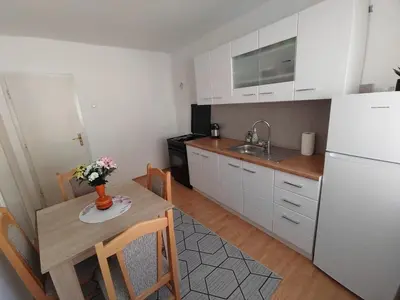 a kitchen with a table and a white refrigerator at VERANIJE Apartman in Livno